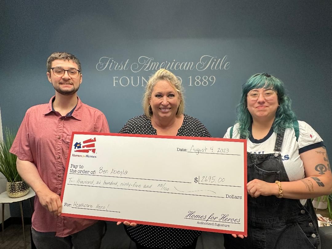 Three people holding a large check in front of a wall.